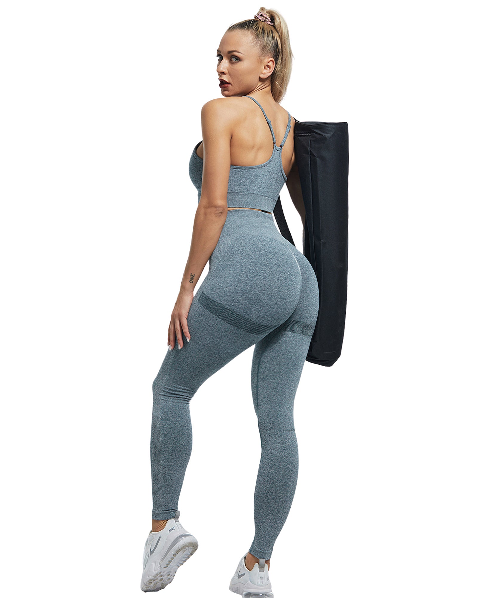 girl wearing gray yoga pants and top holding a bag with a white background